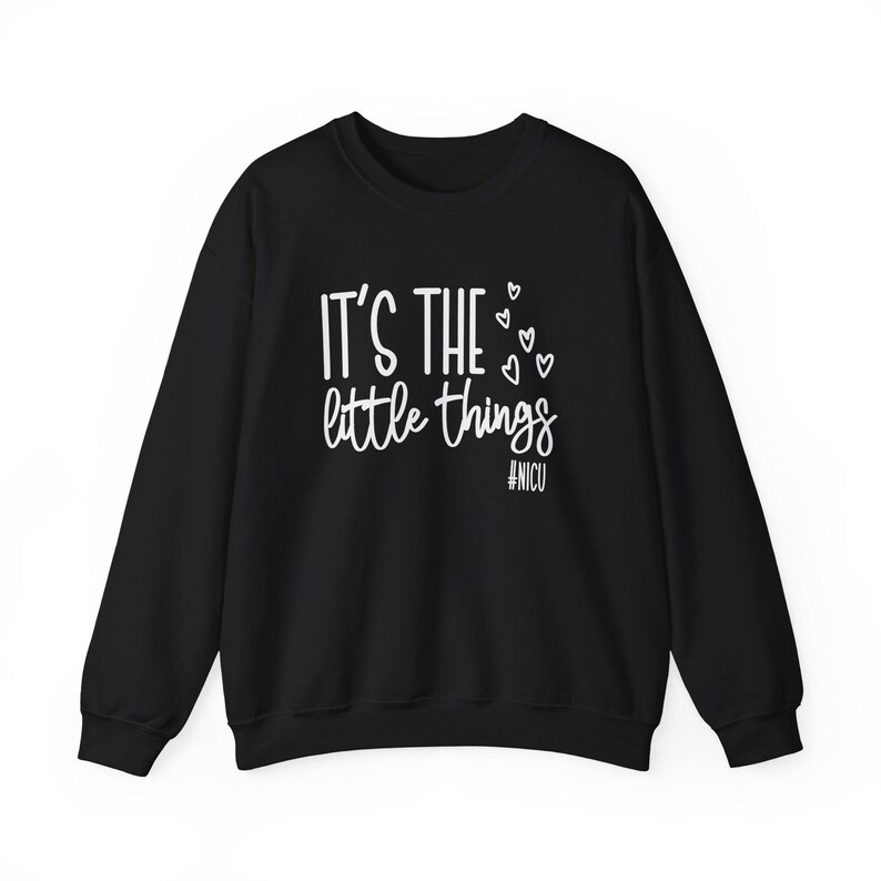 Może przedstawiać: Czarna bluza z okrągłym dekoltem z białym napisem "IT'S THE little things", małymi serduszkami i hasztagiem #NICU. Bluza ma długie rękawy i klasyczny, swobodny styl.
