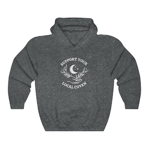 May include: A dark grey hooded sweatshirt with a white graphic design that says "Support Your Local Coven" with a crescent moon and stars in the center.