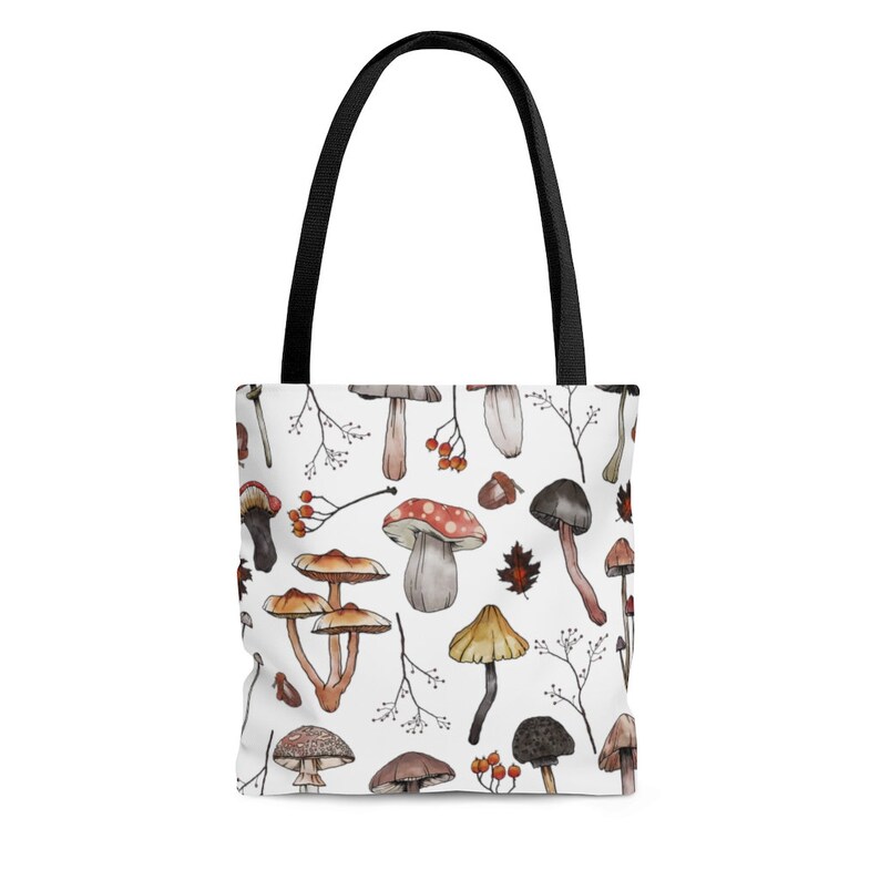 May include: A white tote bag with a pattern of various mushrooms in shades of brown, red, and white. The mushrooms are drawn in a watercolor style and are scattered across the bag.