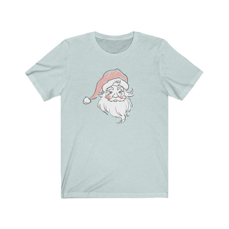 May include: A light blue t-shirt with a vintage-style illustration of Santa Claus's face. The illustration is in shades of pink, white, and gray.