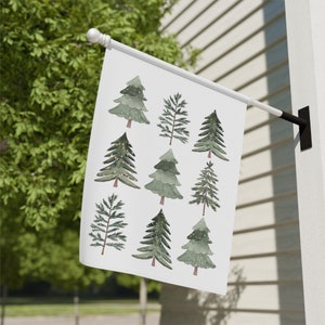 May include: A white flag with a green watercolor design of nine Christmas trees. The trees are decorated with white snow and some have small yellow lights.