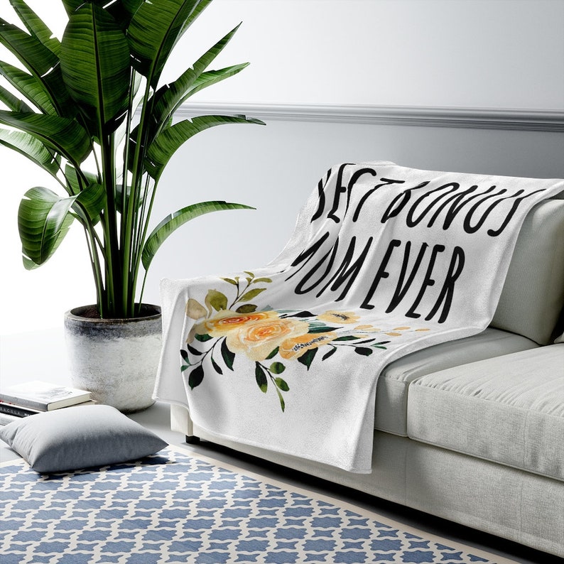 May include: White throw blanket with a floral design and the text "Best Donuts Ever" in black.