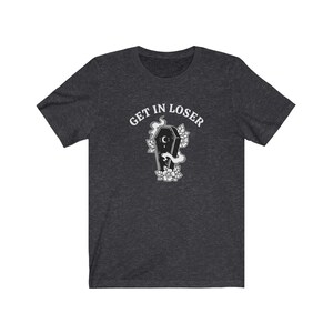 May include: A dark heather grey t-shirt with the text "GET IN LOSER" above a black and white illustration of a coffin with a crescent moon and flowers.