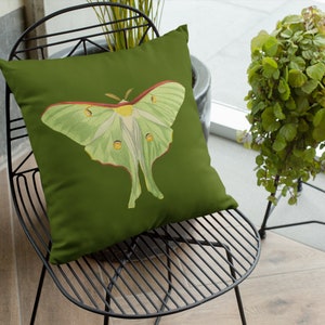May include: A green throw pillow with a green and white luna moth illustration. The pillow is on a black metal chair.