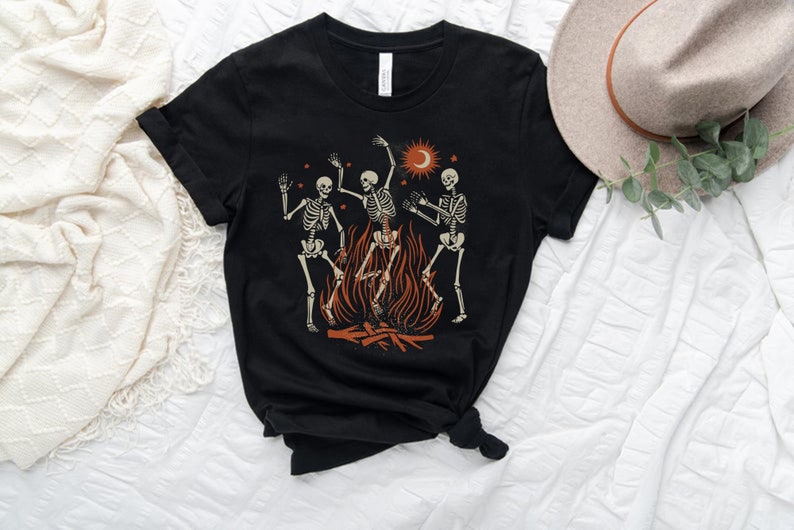 May include: Black t-shirt with a graphic of three skeletons dancing around a campfire with a crescent moon and stars in the background.