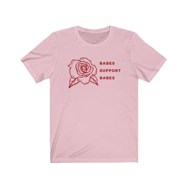 May include: Pink short-sleeved t-shirt with a red rose graphic and the text "BABES SUPPORT BABES".