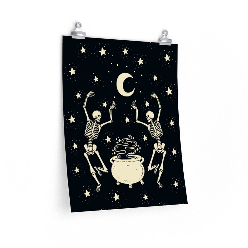 May include: A rectangular wall poster featuring a black background with a cream-colored crescent moon and stars. Two skeletons are depicted dancing around a central cream-colored cauldron emitting swirling smoke, all rendered in a flat graphic style.