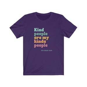 Pu&ograve; includere: Maglietta a maniche corte di colore viola con il testo "Kind people are my kinda people" in colori arcobaleno. Il testo "5th Grade Team" &egrave; stampato sotto il testo principale.