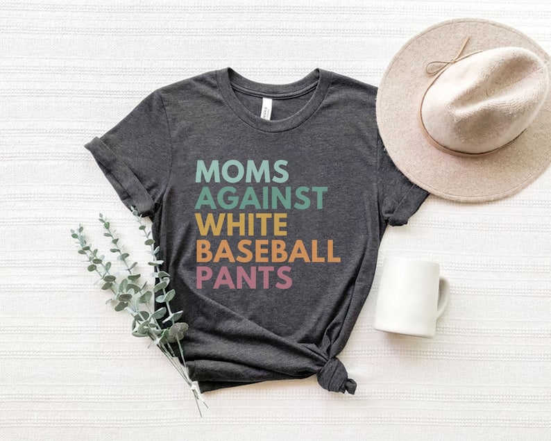 May include: A dark grey t-shirt with the text "MOMS AGAINST WHITE BASEBALL PANTS" printed in colourful letters.