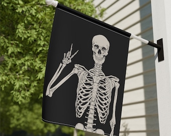 May include: A black flag featuring a white skeleton giving the peace sign. The skeleton is smiling and has a detailed ribcage.