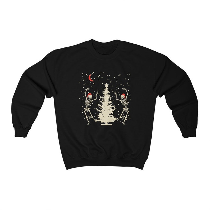 May include: Black sweatshirt with a white Christmas tree and two skeletons wearing Santa hats dancing around it. The background is black with white snowflakes and a crescent moon.