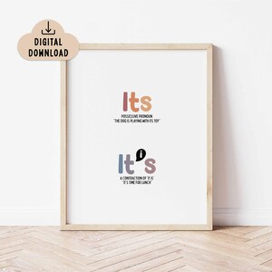 May include: A framed print featuring the words "Its" and "It's" in colourful text. The top text explains the possessive pronoun, and the bottom text explains the contraction. A digital download icon is in the upper left corner.