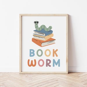 May include: A colorful print with a cartoon worm wearing glasses on top of a stack of books. The text "BOOK WORM" is written below the books in colorful letters.