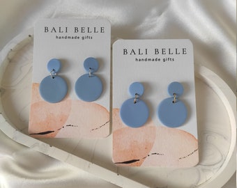 Puede incluir: Dos pares de pendientes redondos de color azul claro en tarjetas blancas con el texto "Bali Belle handmade gifts".