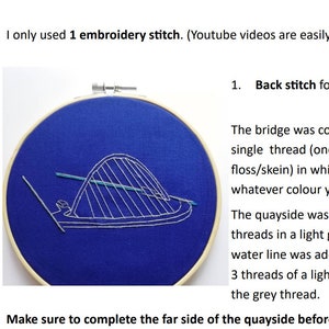 Könnte beinhalten: Nahaufnahme eines Stickrahmens mit blauem Hintergrund. Die Stickerei zeigt eine weiße Brücke mit einer blauen Wasserlinie. Der Text "1. Rückstich für" ist auf dem Bild zu sehen.