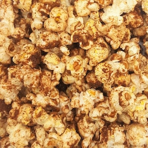 May include: Close-up of a bowl of popcorn with a brown, cinnamon-like coating.