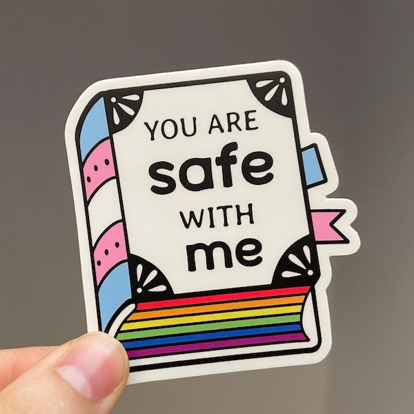 May include: A white sticker with a rainbow stripe at the bottom. The sticker says "You are safe with me" in black text. The sticker has a pink and blue striped border with a white background.