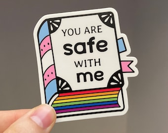 May include: A white sticker with a rainbow stripe at the bottom. The sticker says "You are safe with me" in black text. The sticker has a pink and blue striped border with a white background.