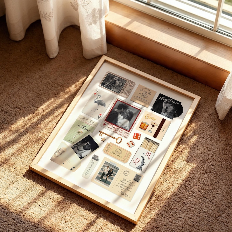 May include: A framed collection of vintage-style cards, photos, and ephemera. The items include a key, playing cards, a photo of a couple, and a matchbox. The frame is light wood, and the items are arranged on a white background.