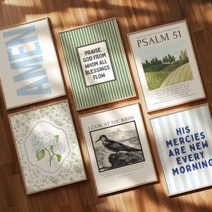 May include: A collection of framed art prints with various designs and text. One print says "AMEN" in light blue, another says "PRAISE GOD FROM WHOM ALL BLESSINGS FLOW". Other prints feature landscapes, floral designs, and inspirational quotes.