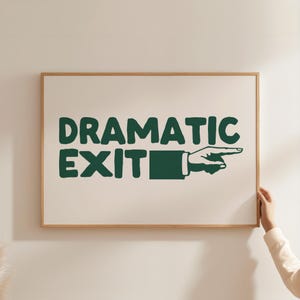 Op de afbeelding: Een ingelijst afdruk met een groene afbeelding van een wijzende hand en de tekst "Dramatic Exit".