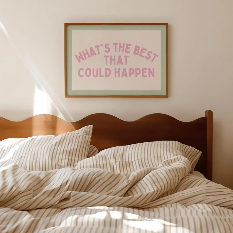 May include: A framed print with the text "WHAT'S THE BEST THAT COULD HAPPEN" in pink lettering. The print is above a bed with striped bedding and a wooden headboard. The room has a neutral color palette.