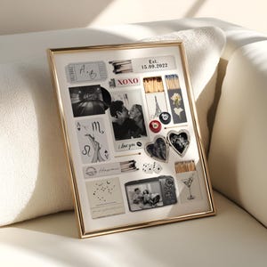 K&ouml;nnte beinhalten: Eine goldgerahmte Collage mit verschiedenen Andenken, darunter Fotos, Spielkarten und Streichh&ouml;lzer. Die Collage enth&auml;lt den Text "Est. 15.09.2022" und "I love you". Das Gesamtthema ist romantisch und sentimental.