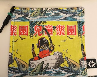 May include: A yellow fabric pouch with a cartoon cat wearing a pirate hat and holding a fishing rod. The cat is in a boat with a fish jumping out of the water. The pouch has the text "冒険 冒険" in Japanese characters.