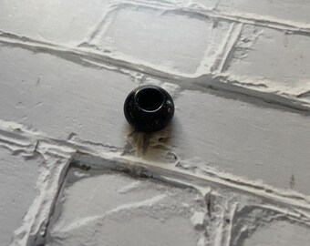 One single black/purple sparkle sandstone bead