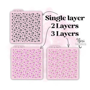 May include: Three images showing different layers of a cookie cutter stencil. The top image shows a single layer of a gray floral pattern. The middle image shows a two-layer stencil with a pink floral pattern. The bottom image shows a three-layer stencil with a pink floral pattern.