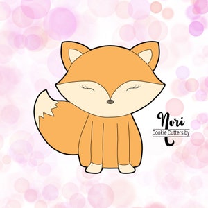 May include: A cartoon fox cookie cutter with closed eyes. The fox is orange with a black outline and a small black nose. The cookie cutter is on a white background with pink circles.