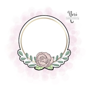 May include: A gold and white circular cookie cutter with a floral design. The cutter features a single rose with green leaves and a scalloped edge.