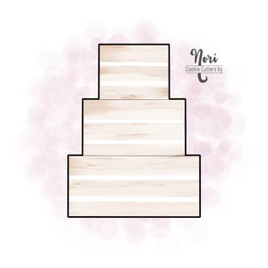 May include: A three-tiered cookie cutter in the shape of a wedding cake. The cutter is made of metal and has a white finish. The text "Nori Cookie Cutters by" is visible in the image.