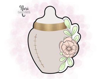 May include: A white baby bottle cookie cutter with a gold band around the top and a pink flower with green leaves on the side.