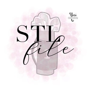 May include: A cookie cutter in the shape of a golf bag with golf clubs sticking out of the top. The bag has a number "1" on it. The text "Stilife" is written in cursive below the bag. The background is a watercolor wash of pink.