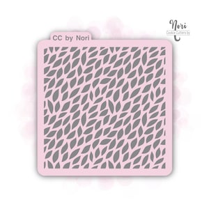 May include: A pink plastic cookie cutter with a pattern of small, gray leaves. The cookie cutter is labeled "CC by Nori" in the top left corner and "Nori Cookie Cutters by" in the top right corner.