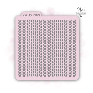 May include: A pink cookie stencil with a gray knit pattern. The stencil has the text "CC by Nori" on the top left and "Nori Cookie Cutters by" on the top right.