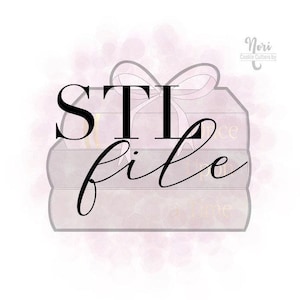 May include: A cookie cutter in the shape of a stack of books with a bow on top. The words "STI file" are written across the books in a black, elegant font. The books are light pink with gold text.