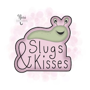 May include: A pink cookie cutter shaped like a slug with the text "Slugs & Kisses" in black cursive font. The slug is green with a smiling face and two black eyes.