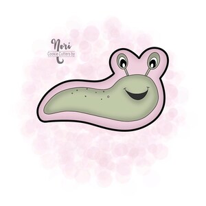May include: A pink and green cookie cutter shaped like a smiling slug with two antennas. The cookie cutter is designed for making cookies. "Nori Cookie Cutters by" is written in the top left corner of the image.