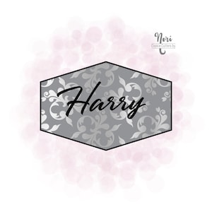 May include: A gray hexagonal cookie cutter with a silver floral pattern and the word "Harry" in black script. The cookie cutter is on a white background with pink watercolor-like circles.