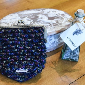 May include: A black crocheted coin purse with iridescent thread, a white oval box with a carved unicorn design, and a glass bottle with a cork top and a label that says "Happiness".