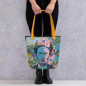 Könnte beinhalten: Eine gelbe Tragetasche mit einem farbenfrohen Bild von Frida Kahlo auf der Vorderseite. Das Bild zeigt Blumen, Pflanzen und den Text "El Mercado".