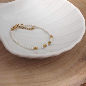 white bracelet with round shell beads and gold steel beads