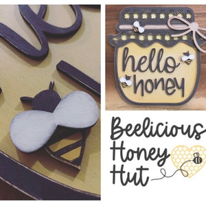 May include: A wooden sign with the text "Beelicious Honey Hut" and a honey jar with the text "hello honey". The sign features a bee and honeycomb design.