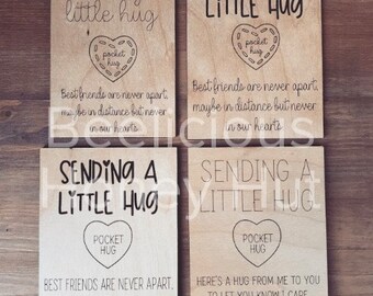 May include: Four wooden signs with the text "Sending a little hug" and a pocket hug design. The signs have different messages about friendship and sending a hug to someone you care about.