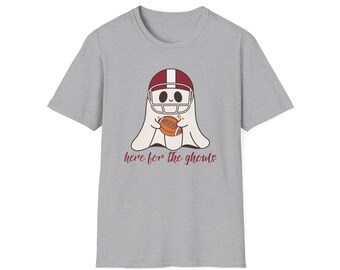 May include: A heather gray t-shirt featuring a cartoon ghost wearing a football helmet and holding a football. The text "here for the ghouls" is printed below the ghost in a maroon color.