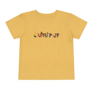 May include: A yellow t-shirt with the word "HUFFLEPUFF" spelled out in colorful letters. Each letter is made up of different images related to the Harry Potter universe.
