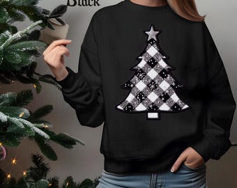 May include: Black sweatshirt featuring a Christmas tree design. The tree is a patchwork of black and white checkered squares with silver glitter accents and a silver star on top. The word "Black" is printed in the upper left corner.