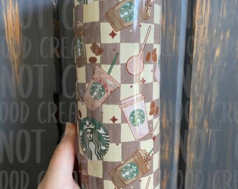 May include: A stainless steel tumbler with a brown and white checkered pattern featuring a repeated design of coffee cups with the Starbucks logo, coffee beans, and spoons.